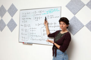 Monica spiega alla lavagna un esercizio di matematica